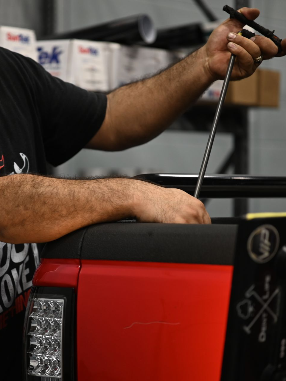 Person in black shirt and red scarf carefully working with clear plastic on a white surface.
