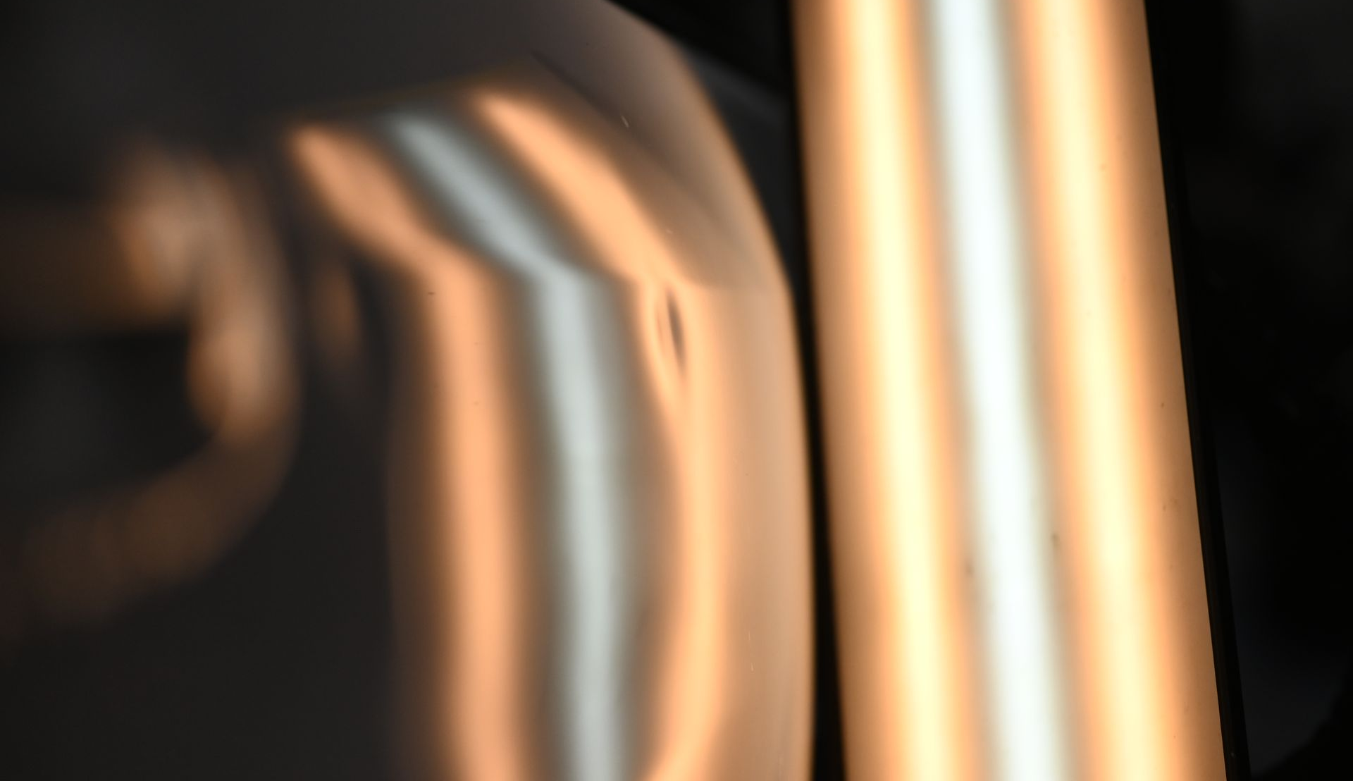 Abstract close-up of blurred metallic gold and black curved surfaces with reflective highlights