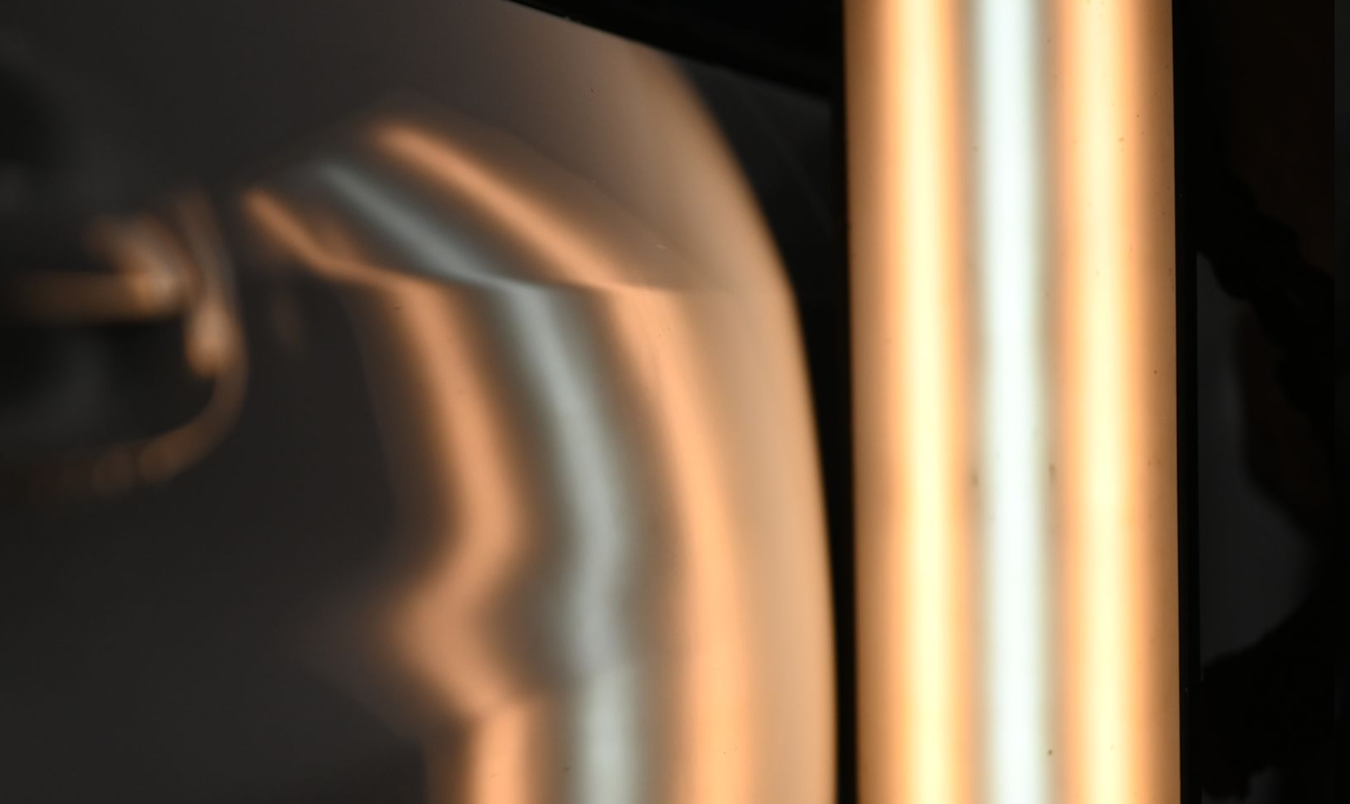 Abstract close-up of blurred copper and gold vertical reflections on a dark background