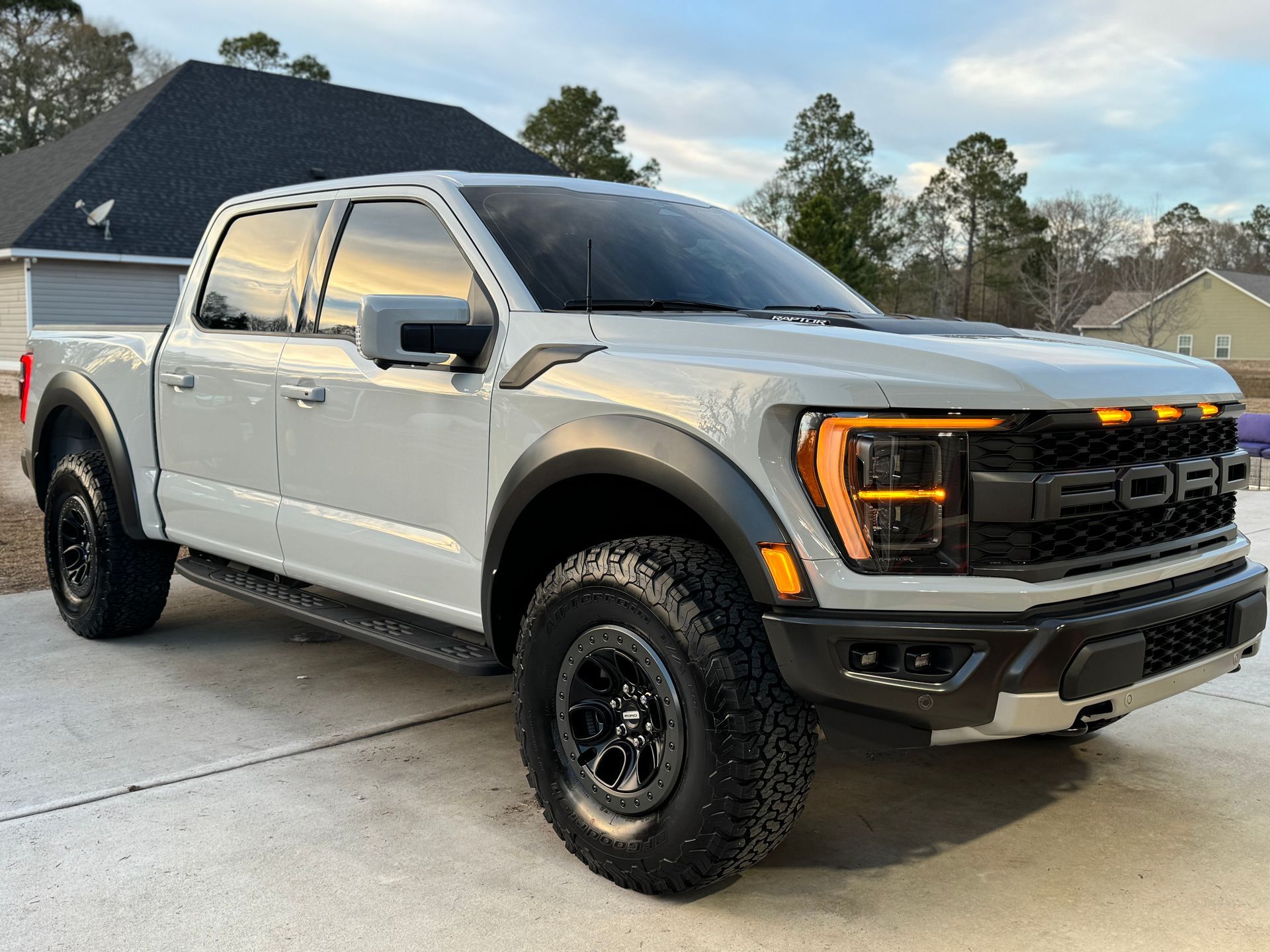Gray Ford Raptor pickup truck parked on concrete driveway.