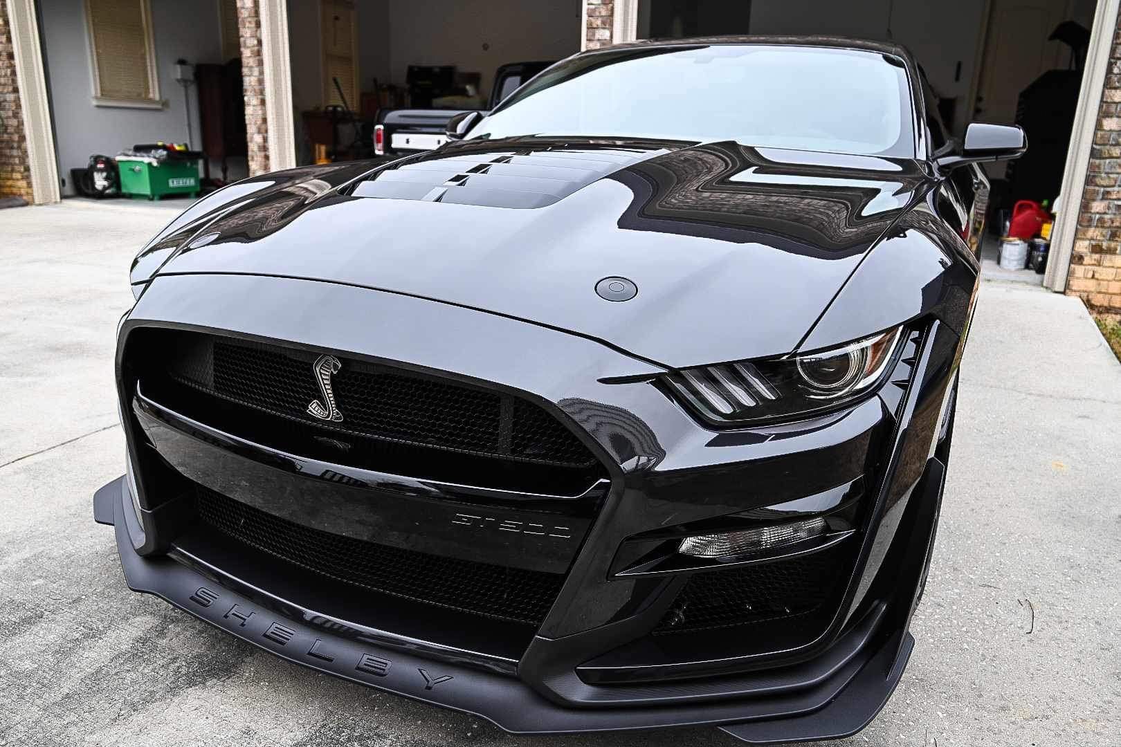 A black ford mustang is parked in a garage after full vehicle detailing