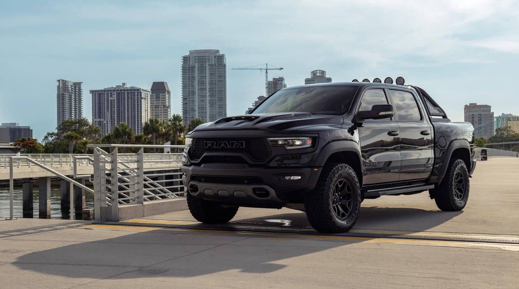 A black ram truck is parked in front of a city skyline.