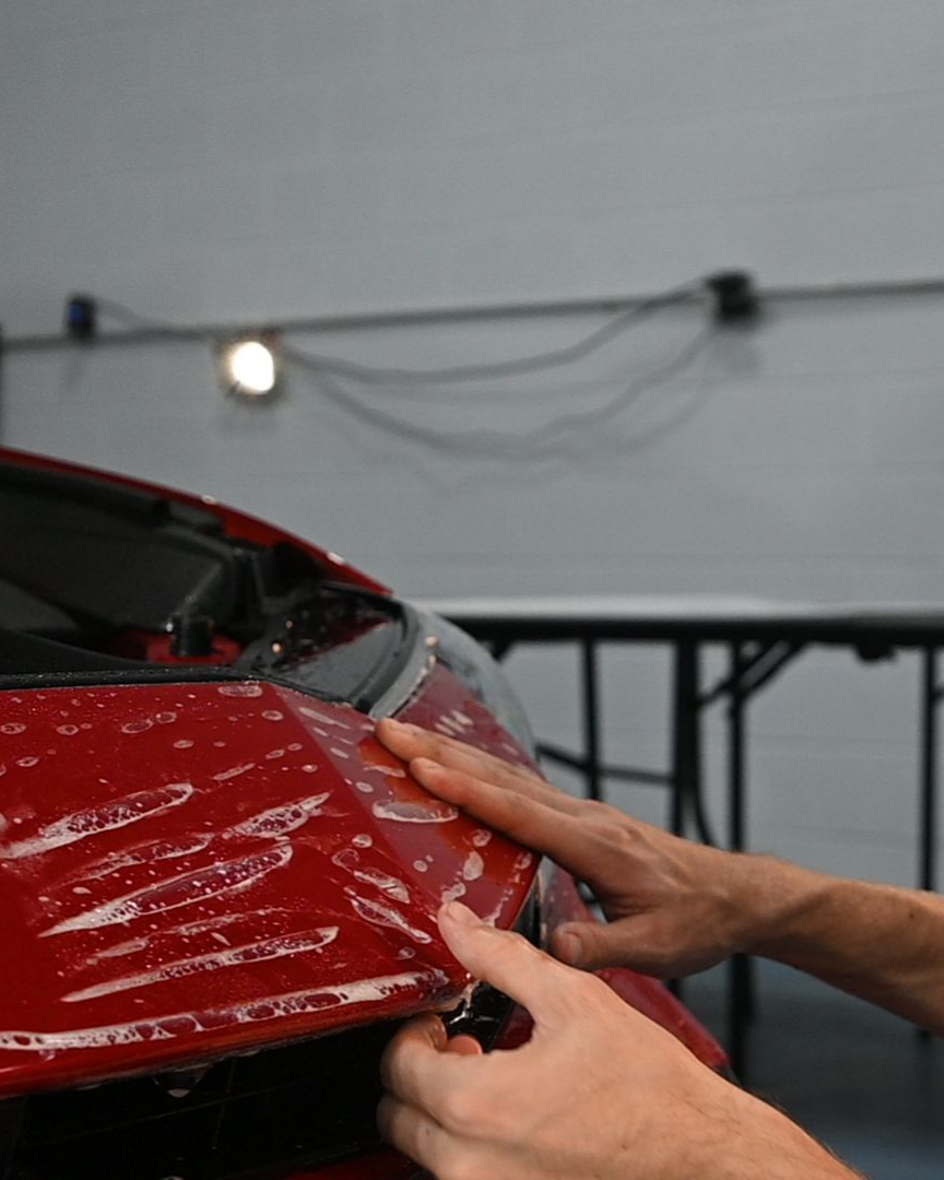 Hands repairing the red front of a car in a workshop