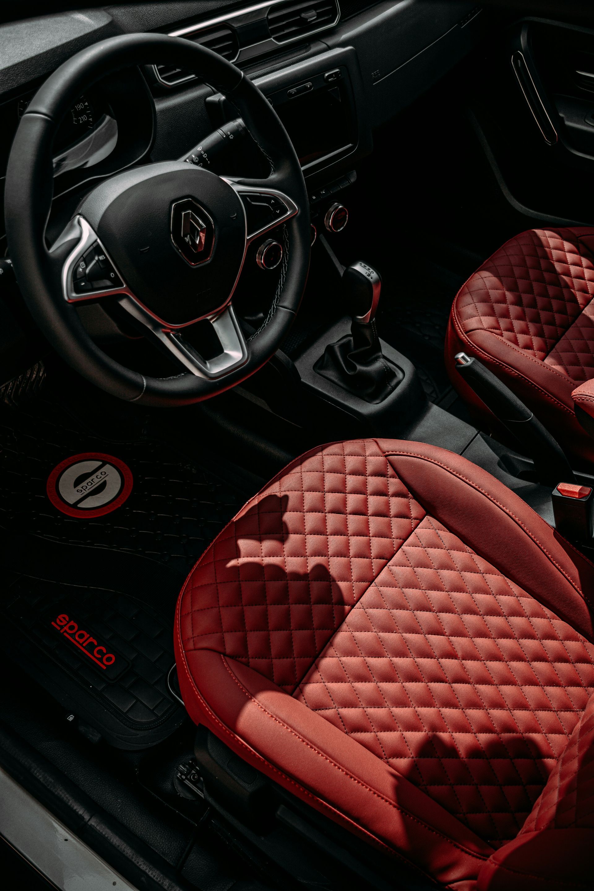 Red quilted car seats and steering wheel with red-black interior and manual gear shift.