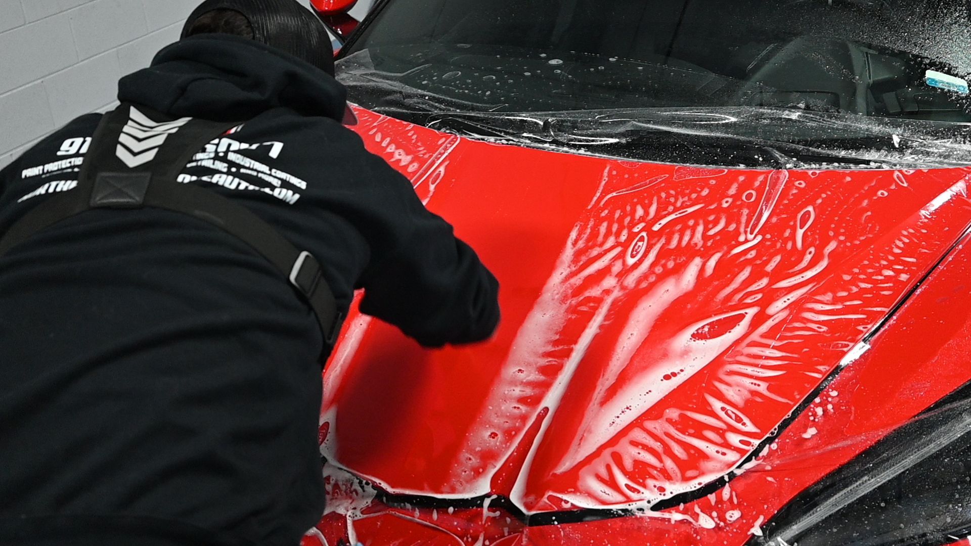 Mechanic applying paint protection film in Northern Lights Home & Auto Coatings—illustrating the process behind is paint protection film worth it.