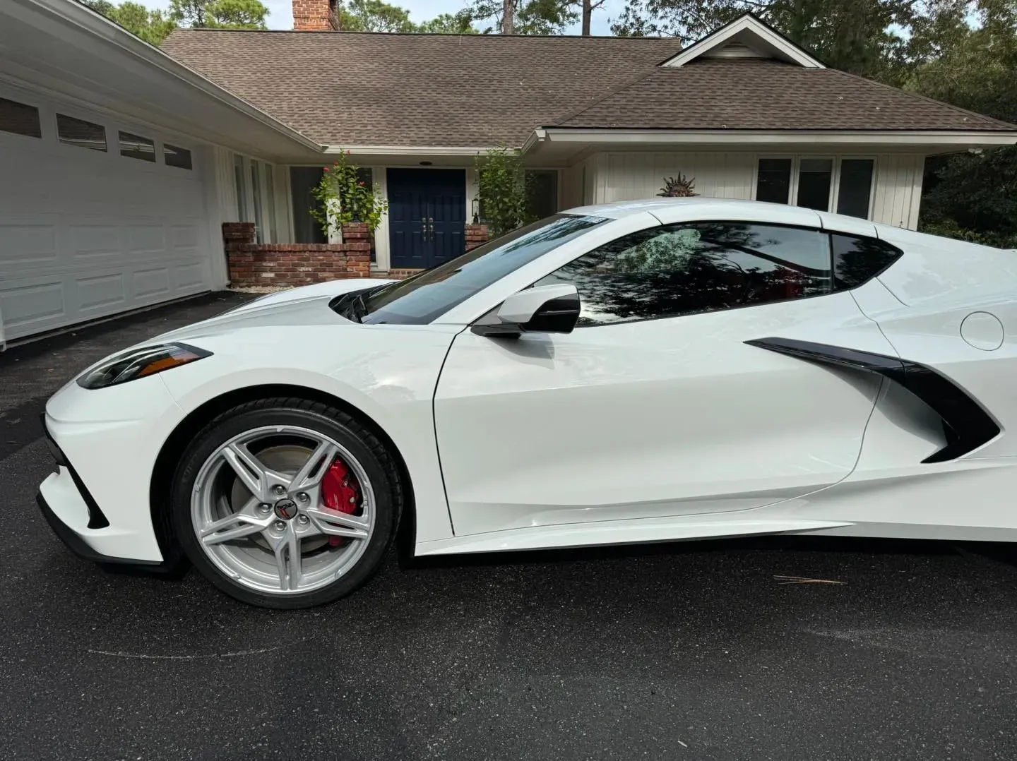 White sports car parked in a driveway in front of a house