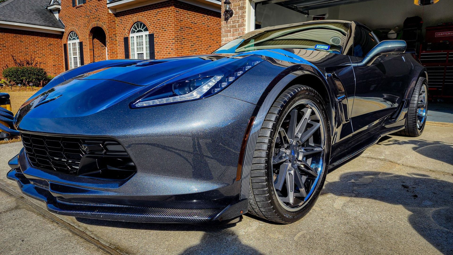 Blue sports car parked outside a brick building in bright sunlight