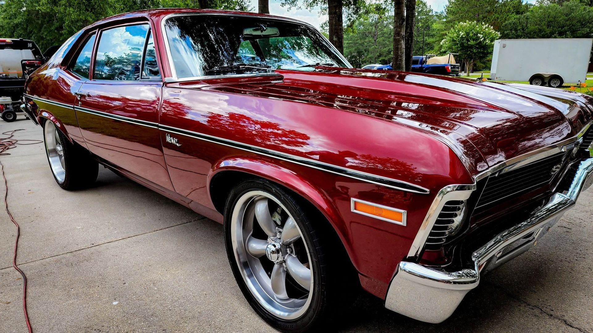 Maroon classic car parked outdoors, angled front view with chrome trim and polished wheels