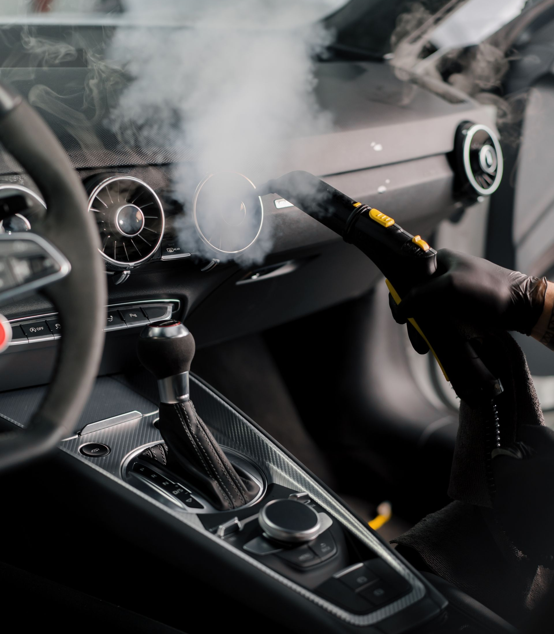 Steering wheel and dashboard in a car interior as smoke billows from the center console