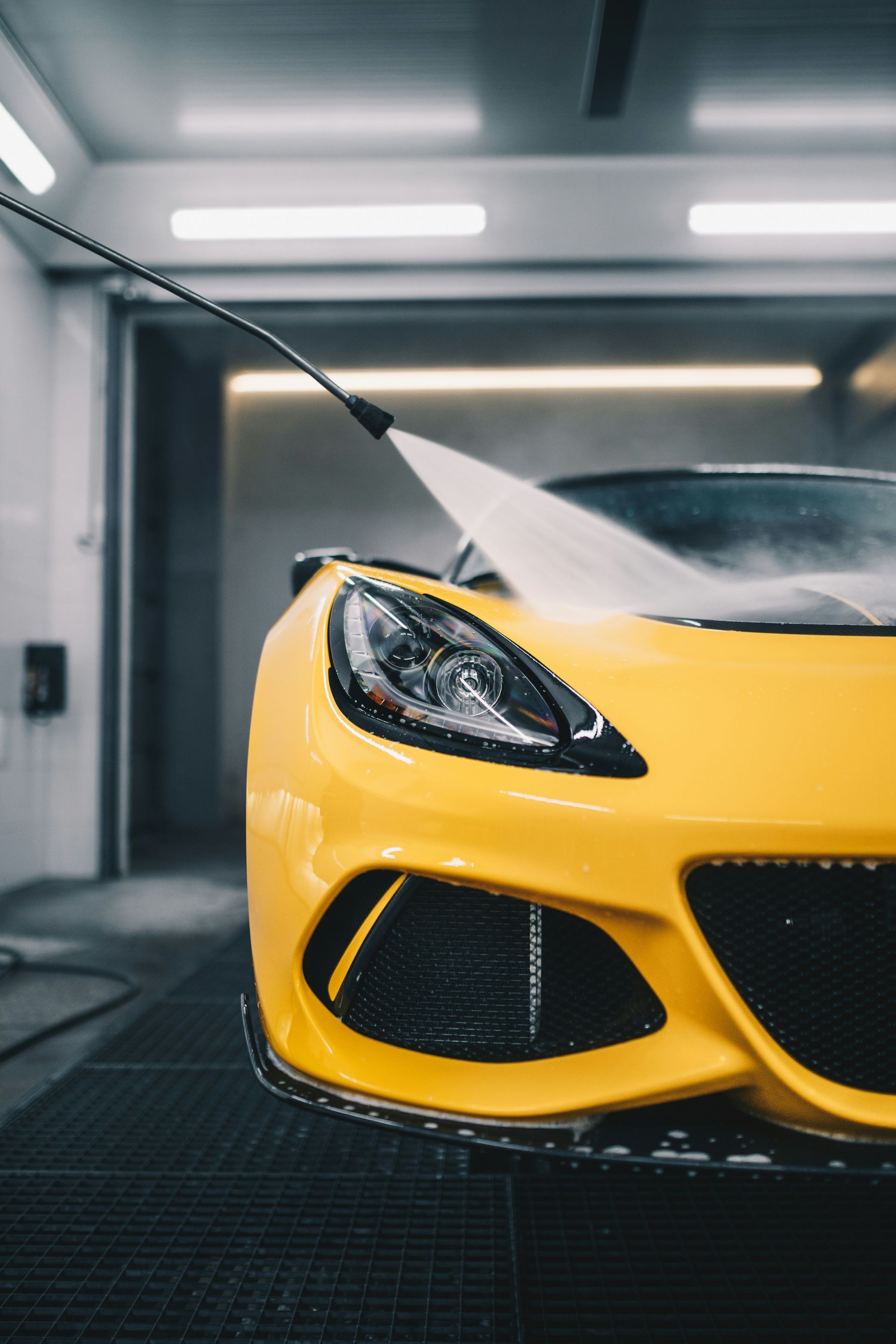 Yellow sports car being washed in a car wash bay