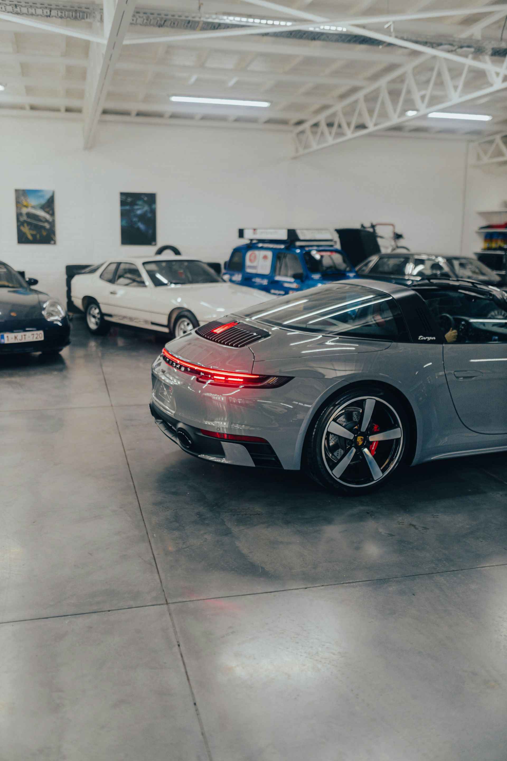 Silver sports car in a showroom with other classic cars and bright overhead lighting