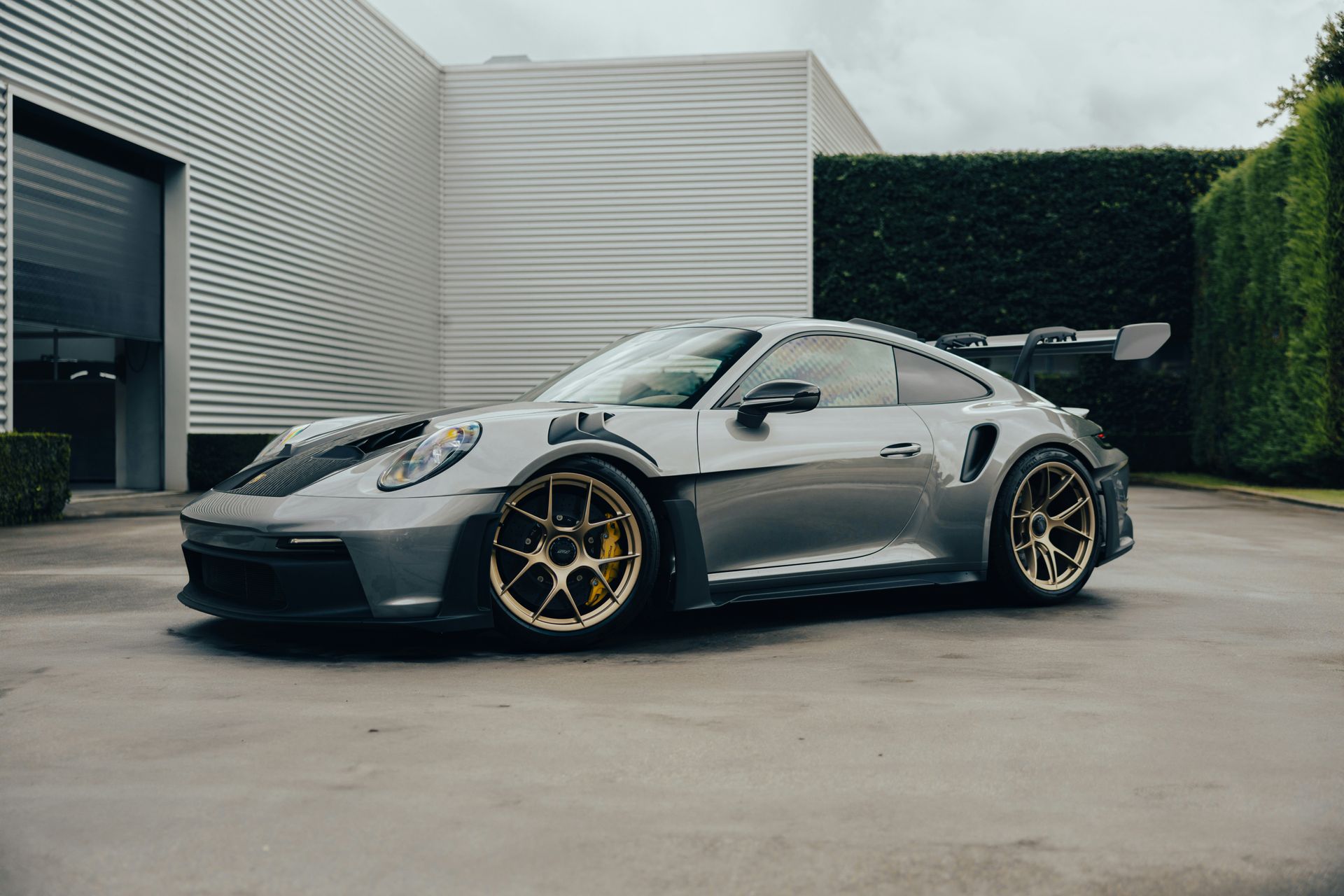 Silver sports car with gold wheels parked in a modern driveway