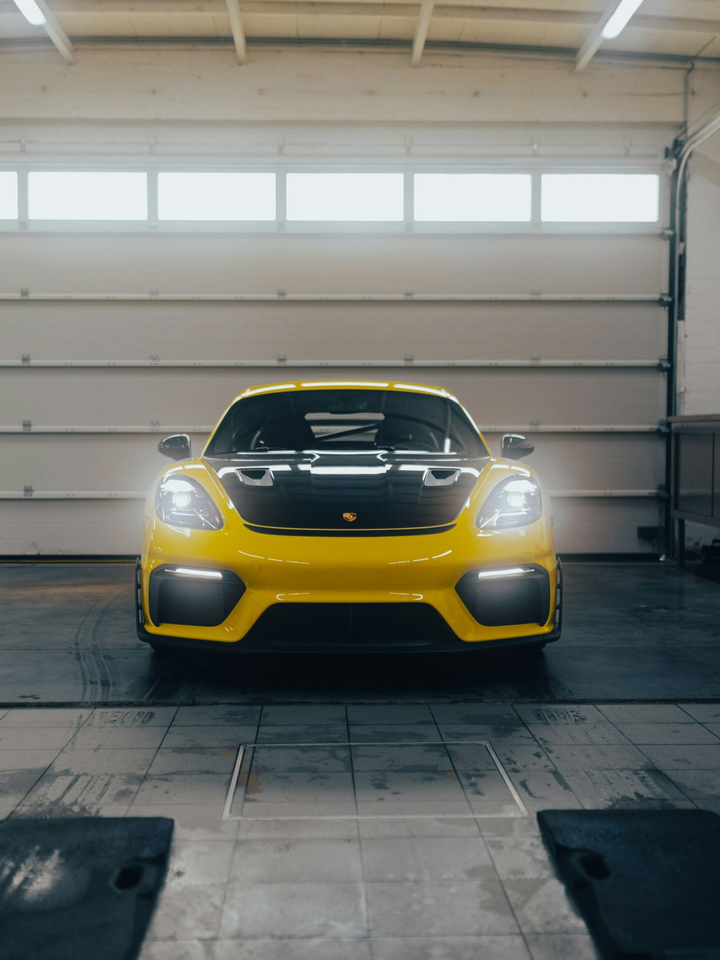 Yellow sports car with headlights on in a garage, front view