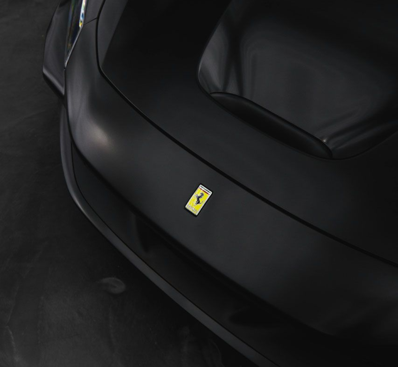 Close-up of a black Ferrari front bumper with the yellow prancing horse emblem