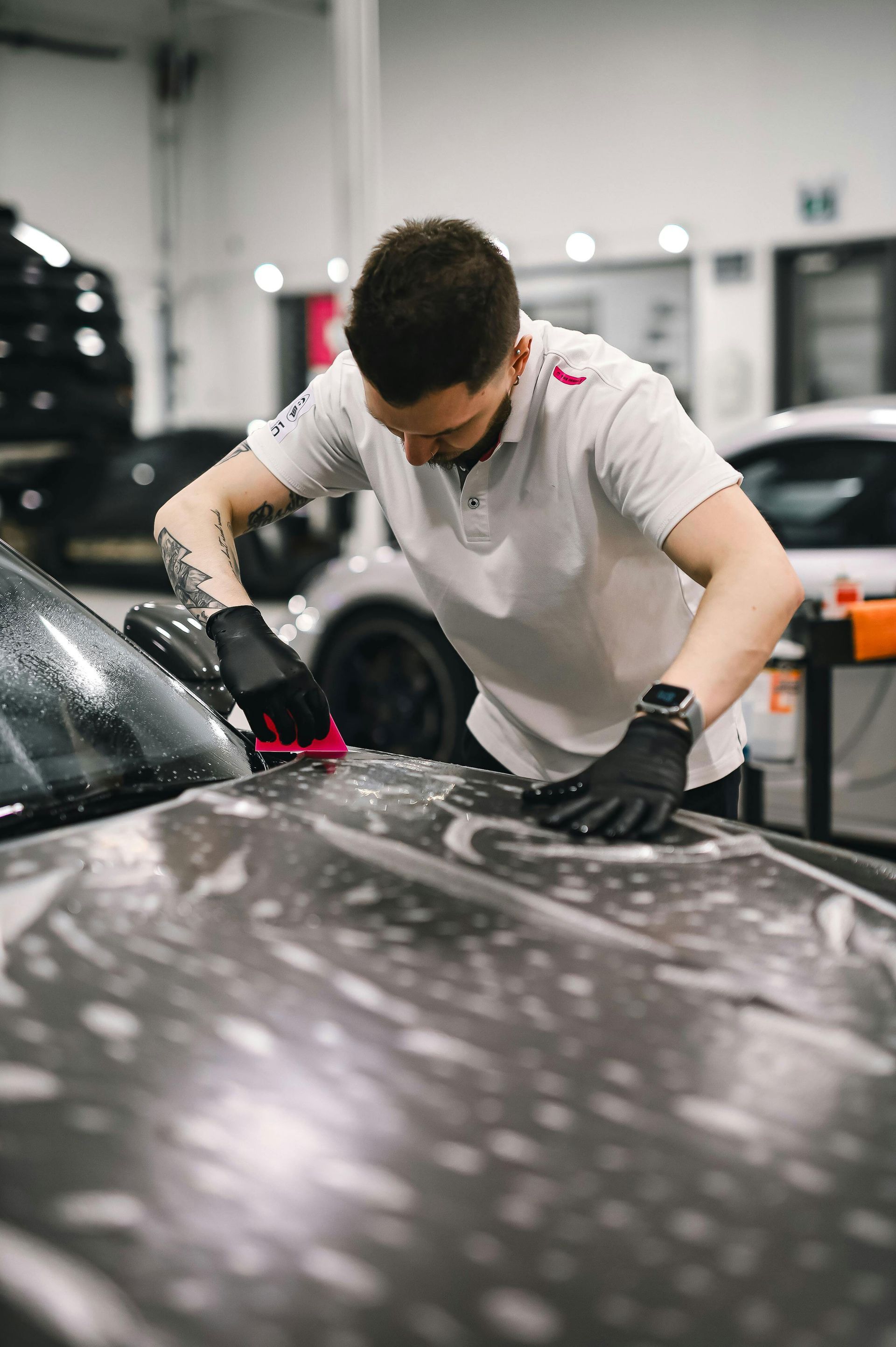 Person cleaning a black car with a red cloth in an auto repair shop