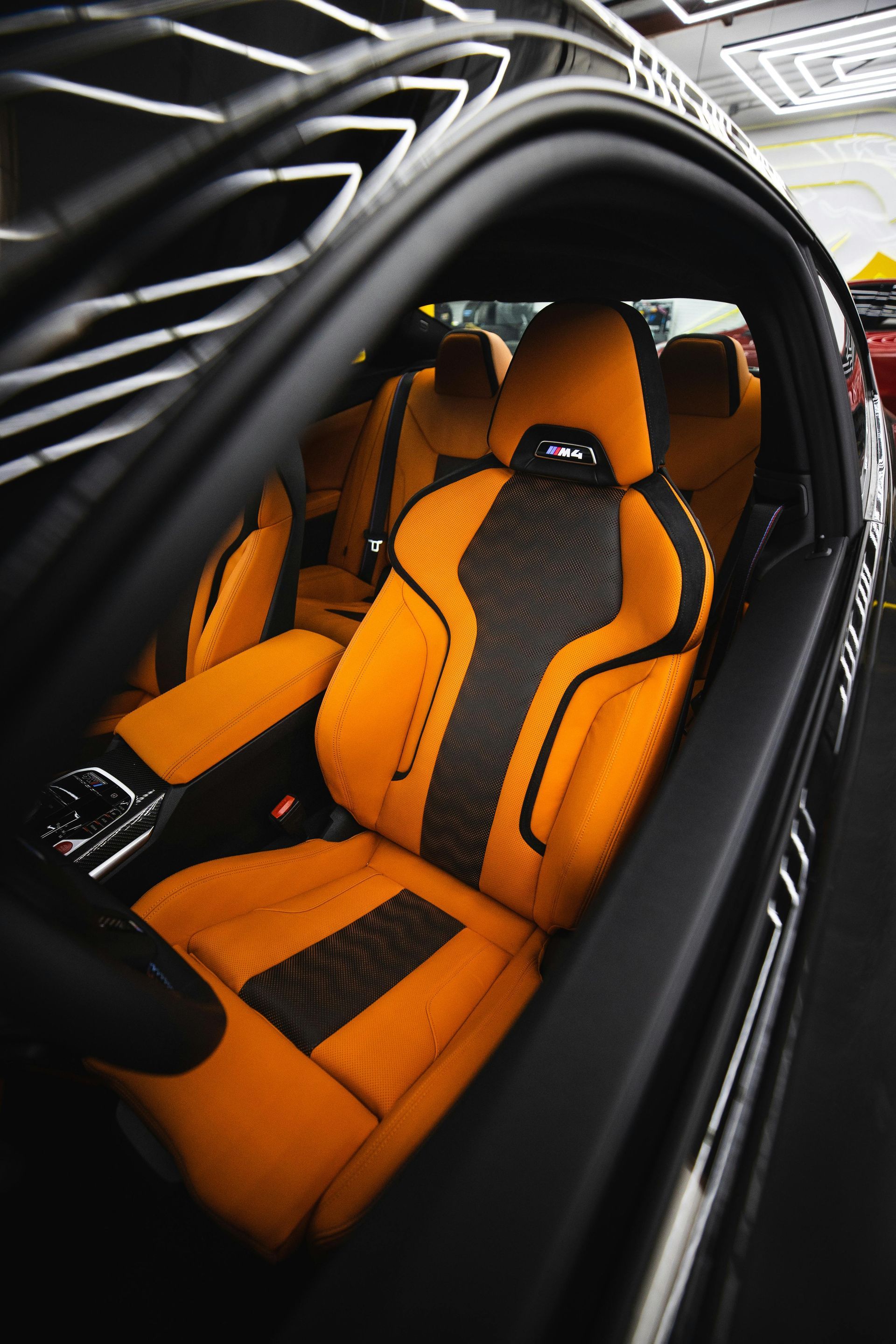 Orange racing-style car seats inside a black vehicle interior, viewed through the open door.