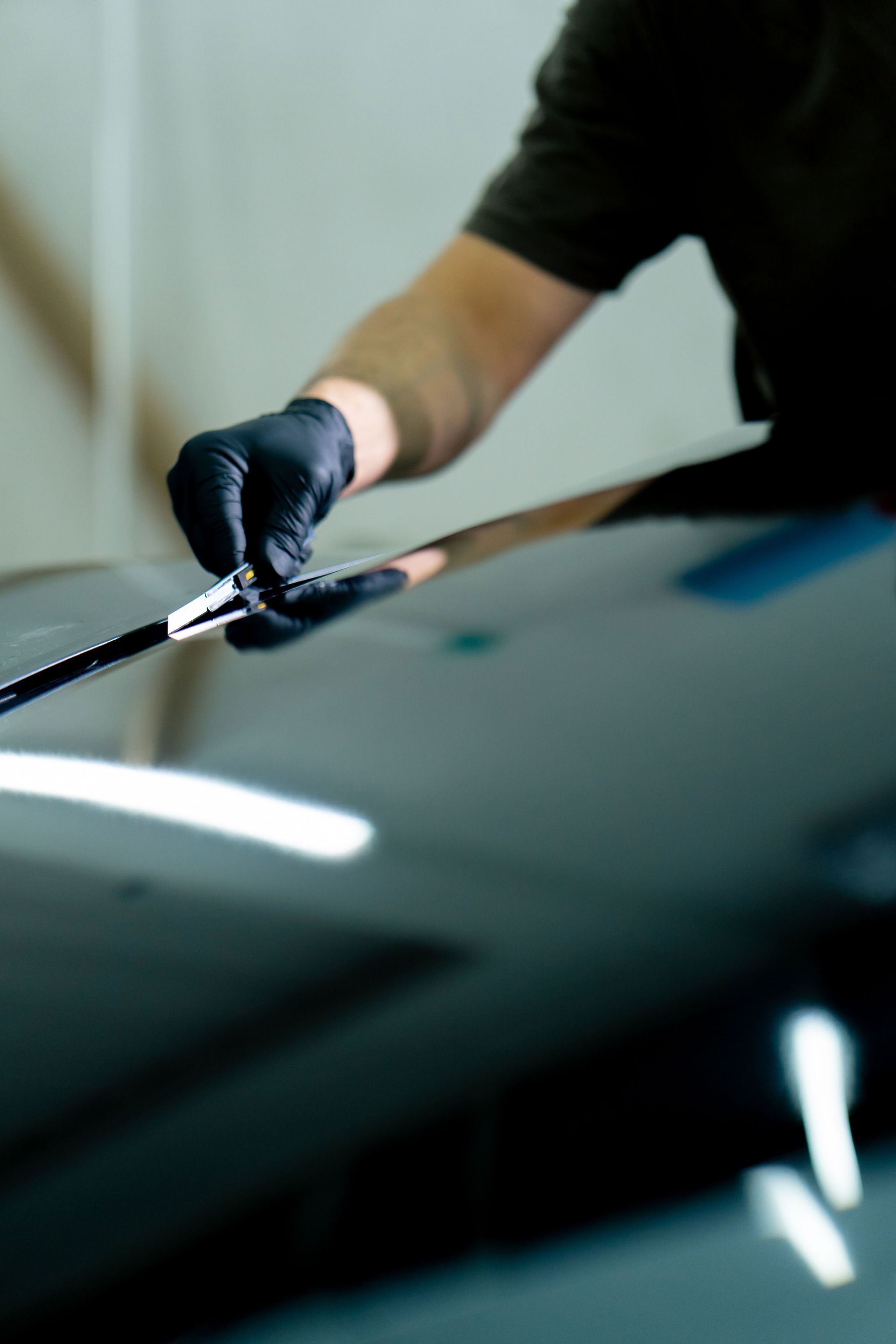 Gloved hand applying polish to a car windshield with a cloth
