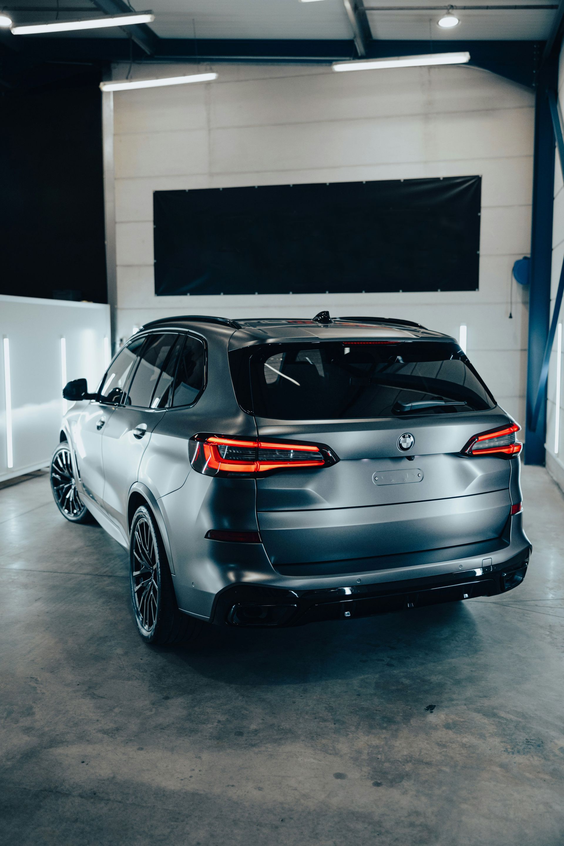 Silver SUV parked indoors in a garage, viewed from the rear.