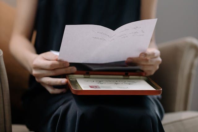 A person holding a letter over a keepsake box creates a tender and reflective scene for cremation services Burnsville, MN