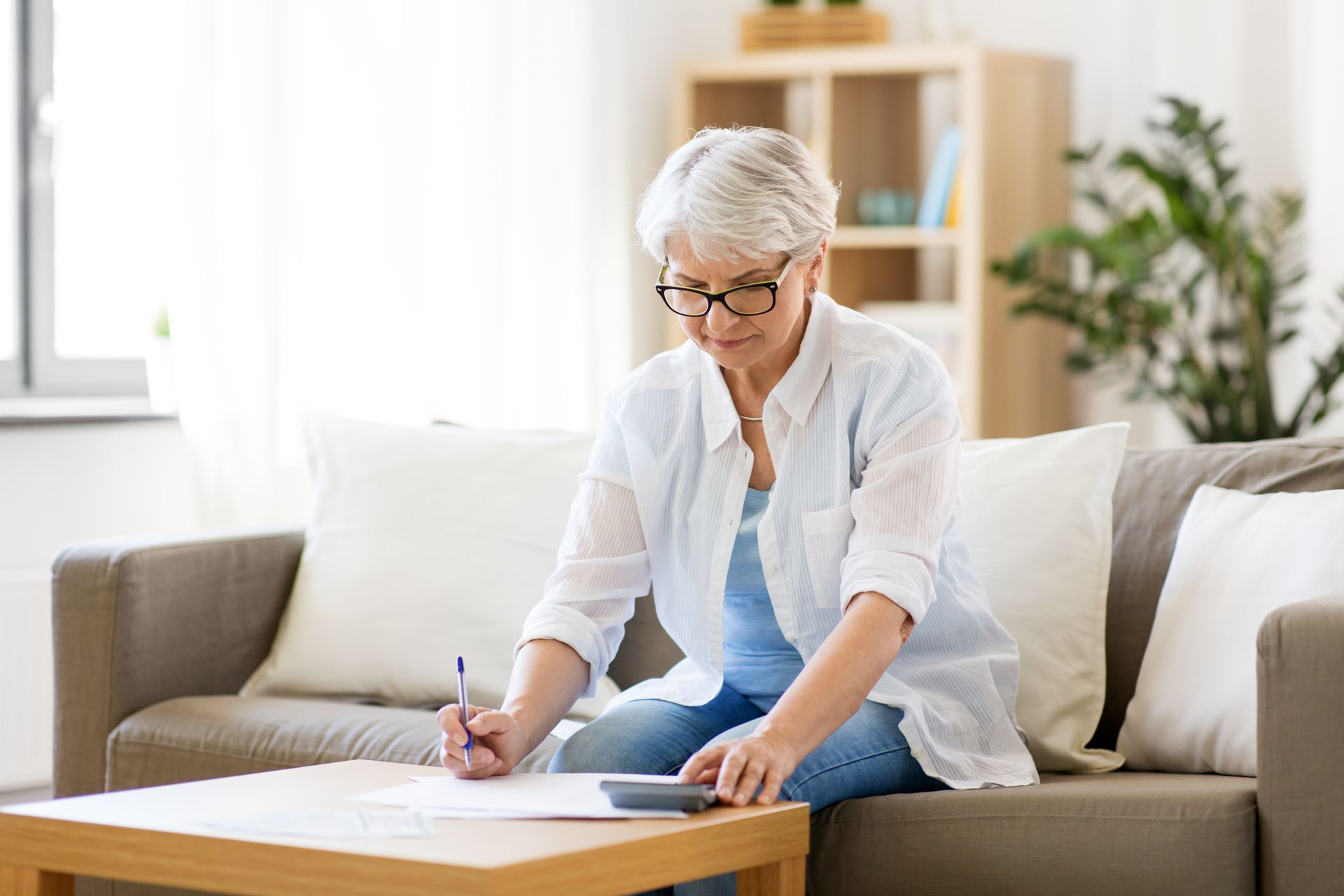 Person writing on paper at a coffee table in a bright living room