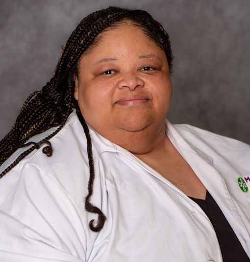 Portrait of a person in a white coat against a gray studio backdrop
