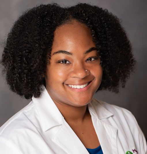 Smiling professional in white coat against a gray studio background