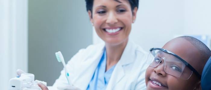 Dentist smiling with a young patient wearing safety glasses during a dental checkup