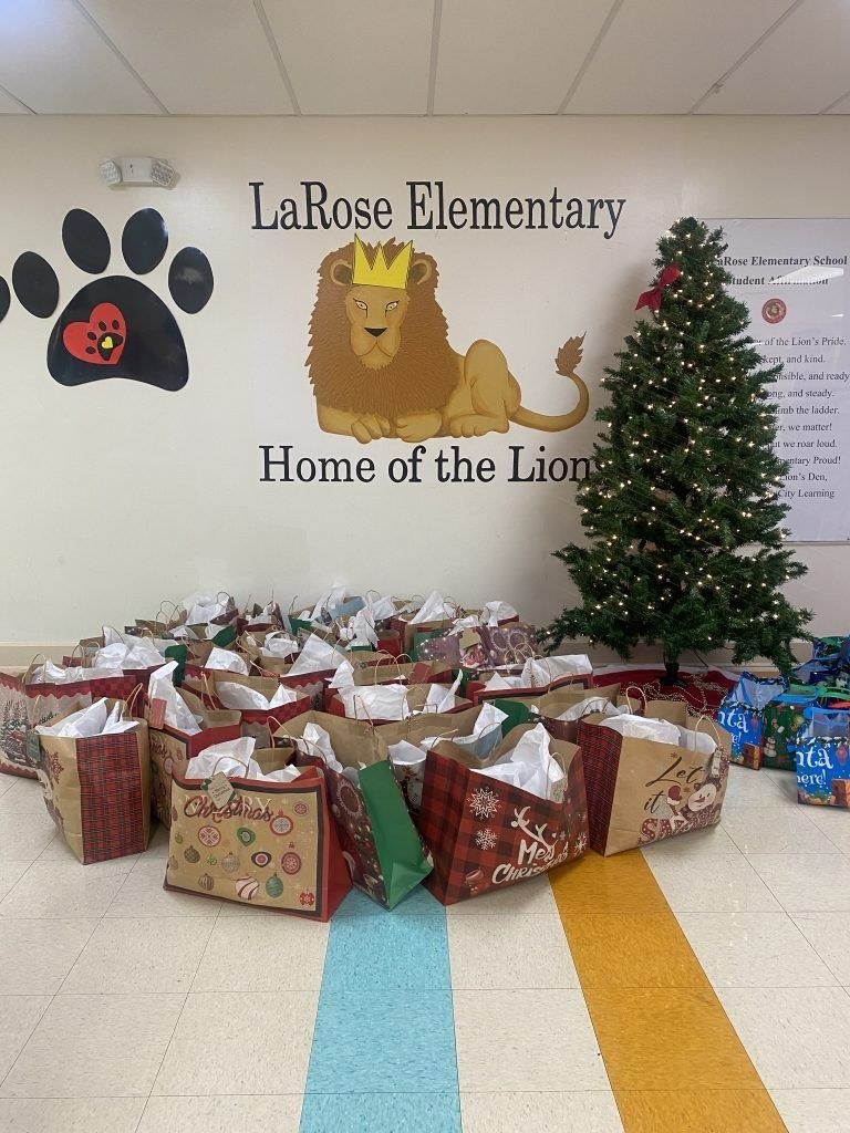 LaRose Elementary wall mural, Christmas tree, and piles of wrapped gifts in a school hallway