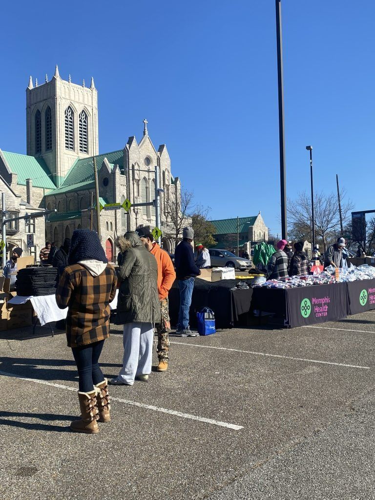 People walking toward a market setup outside a large stone church on a sunny day
