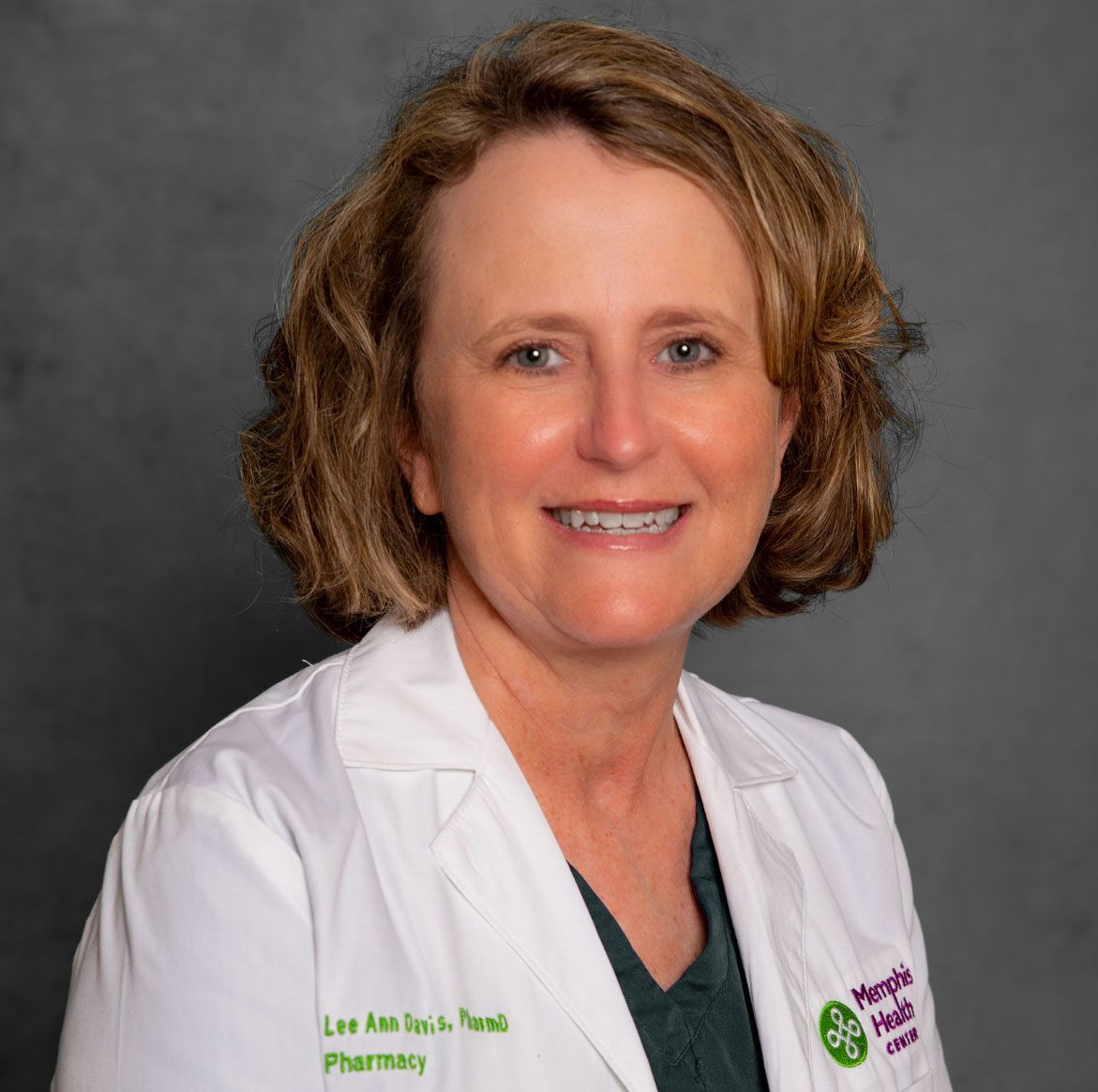 Portrait of a smiling healthcare professional in a white coat against a gray background