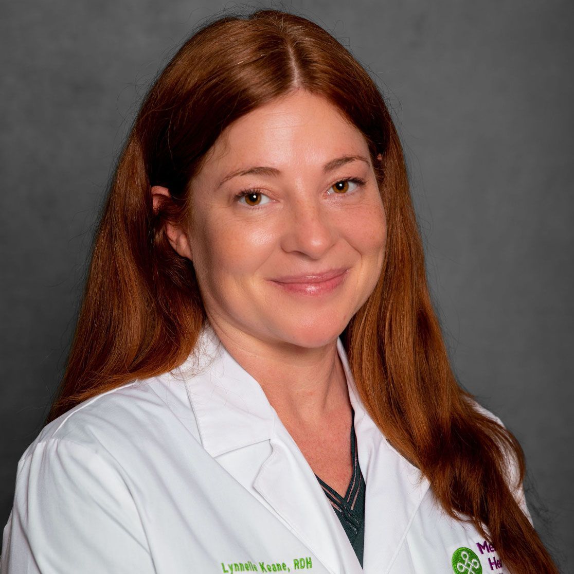 Portrait of a smiling woman in a white lab coat against a gray background