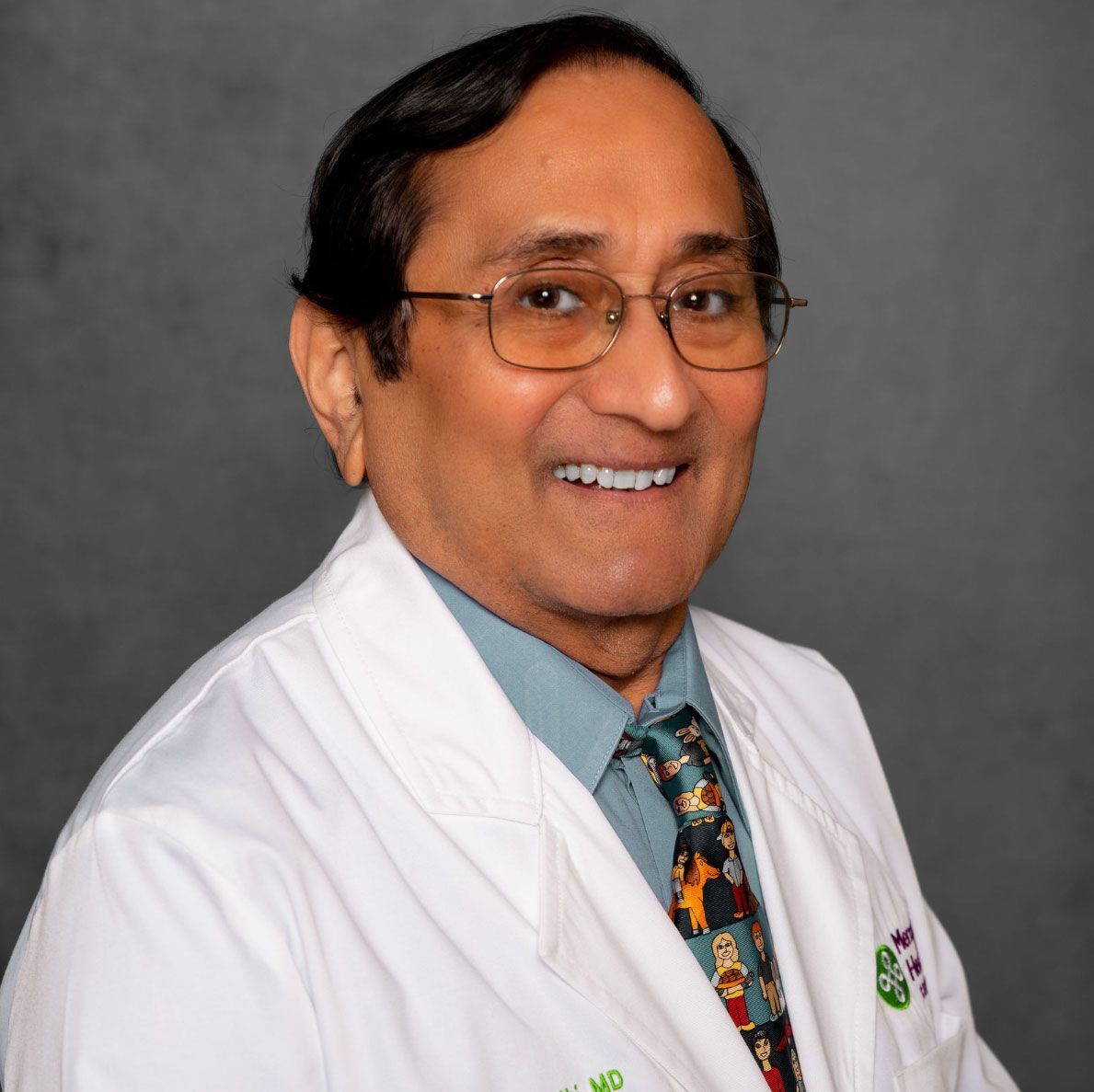 Smiling doctor in white coat and glasses against a gray background