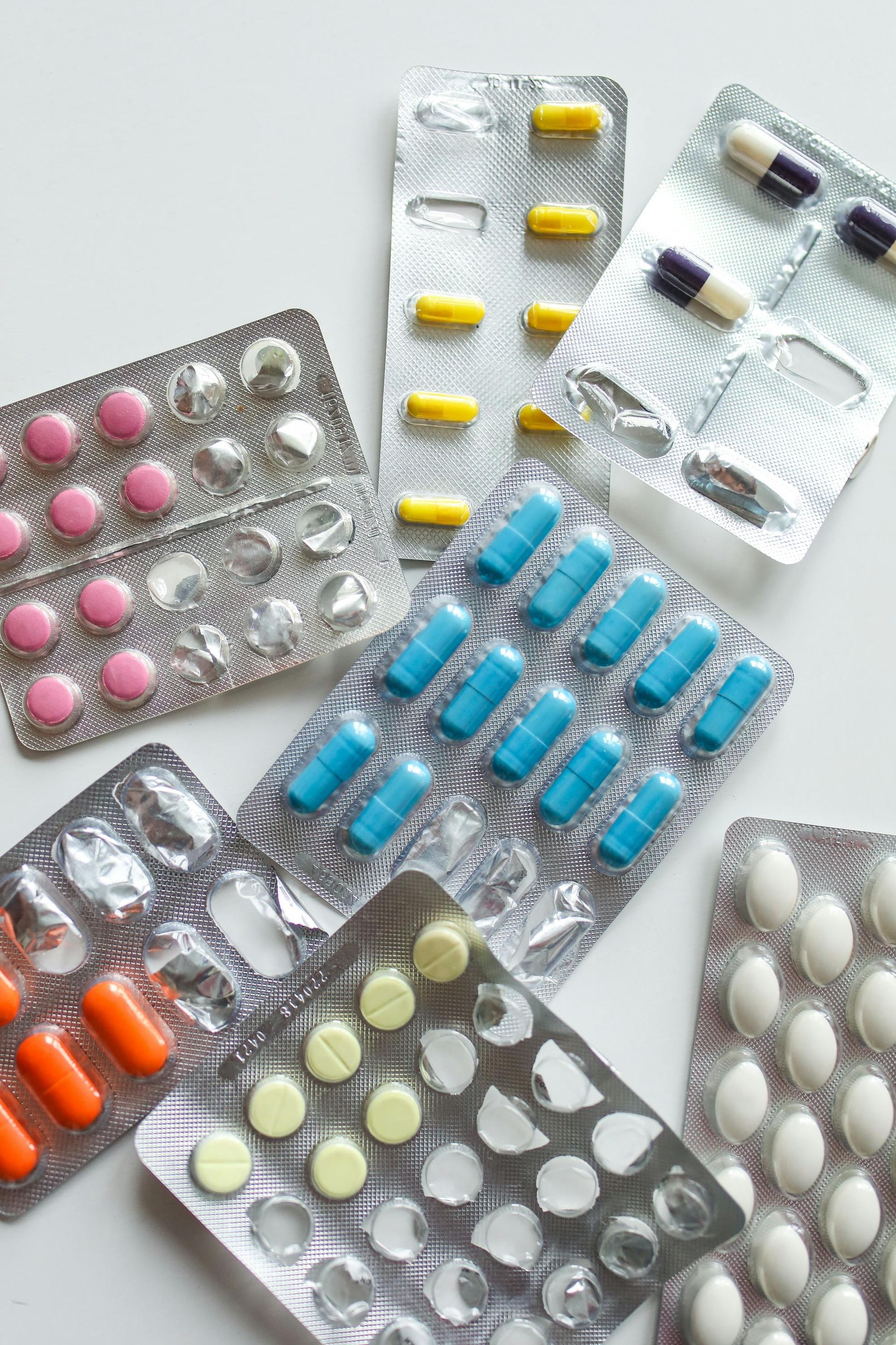 Assorted colorful tablets in blister packs scattered on a white background