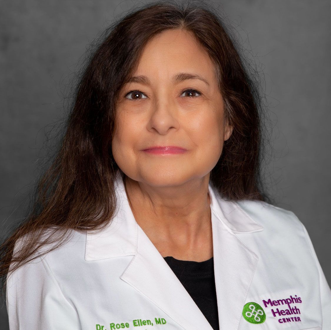 Professional headshot of a doctor in a white coat against a gray background