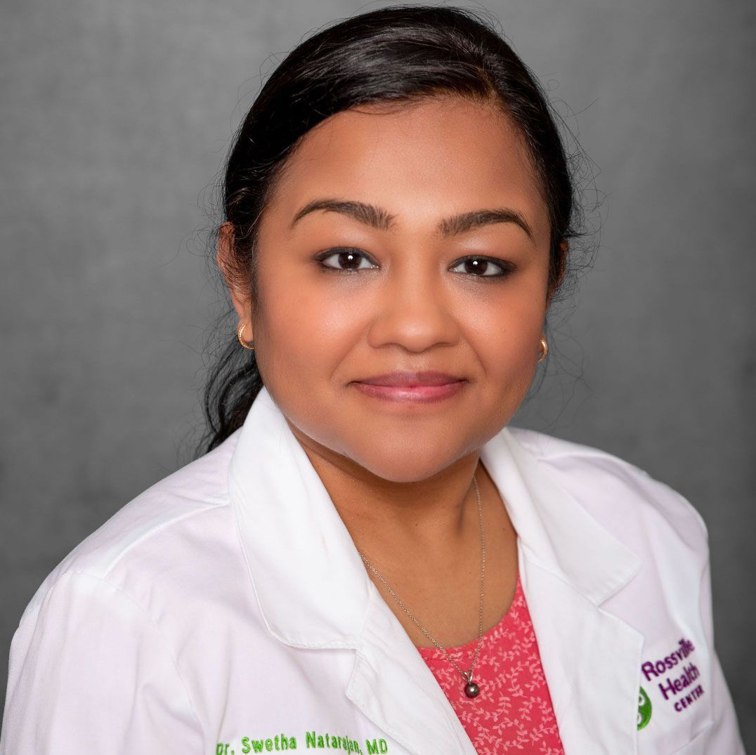 Portrait of a woman in a white medical coat against a gray background