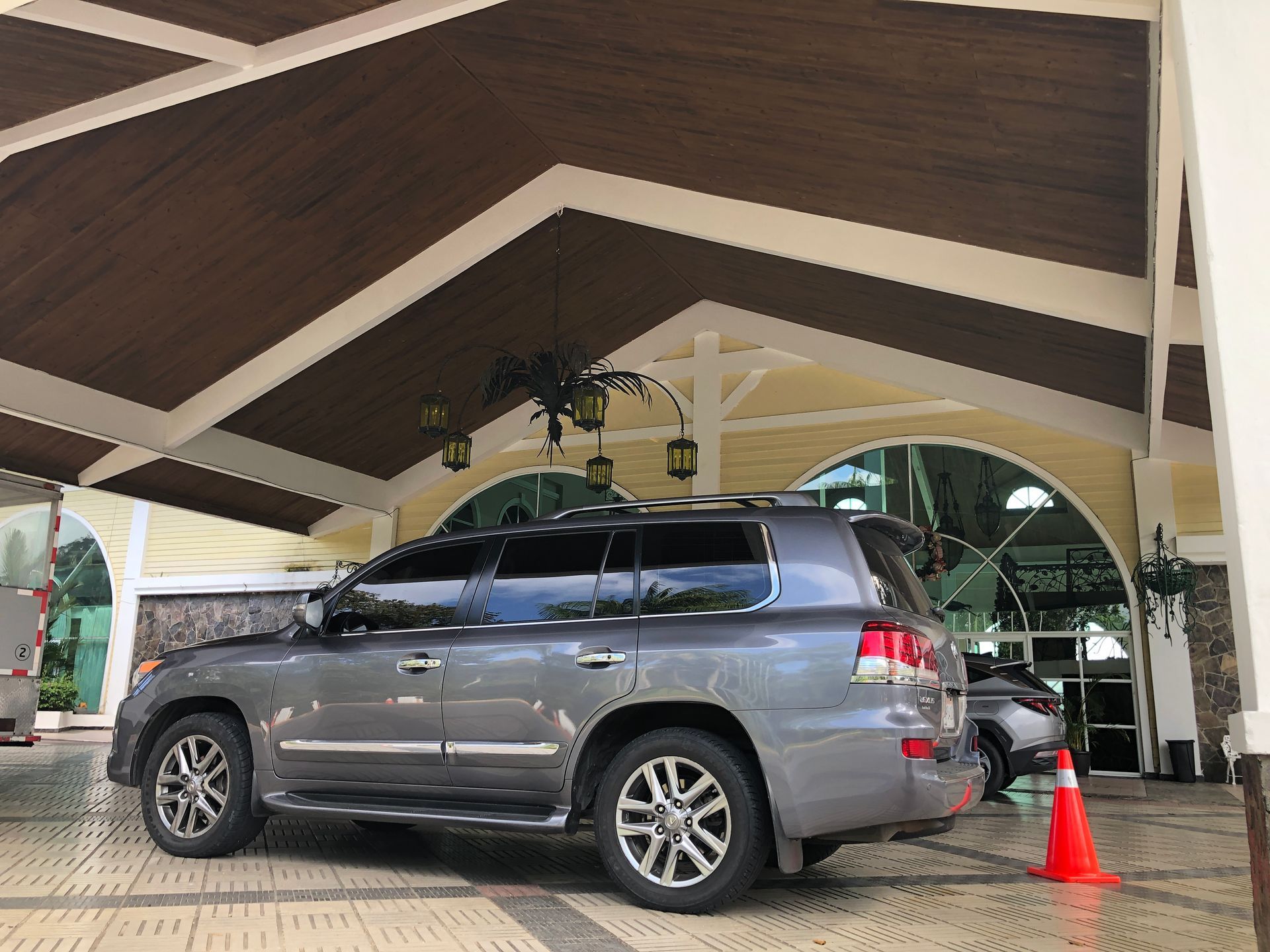 Gray SUV parked under a covered entrance with yellow walls and brown beams.