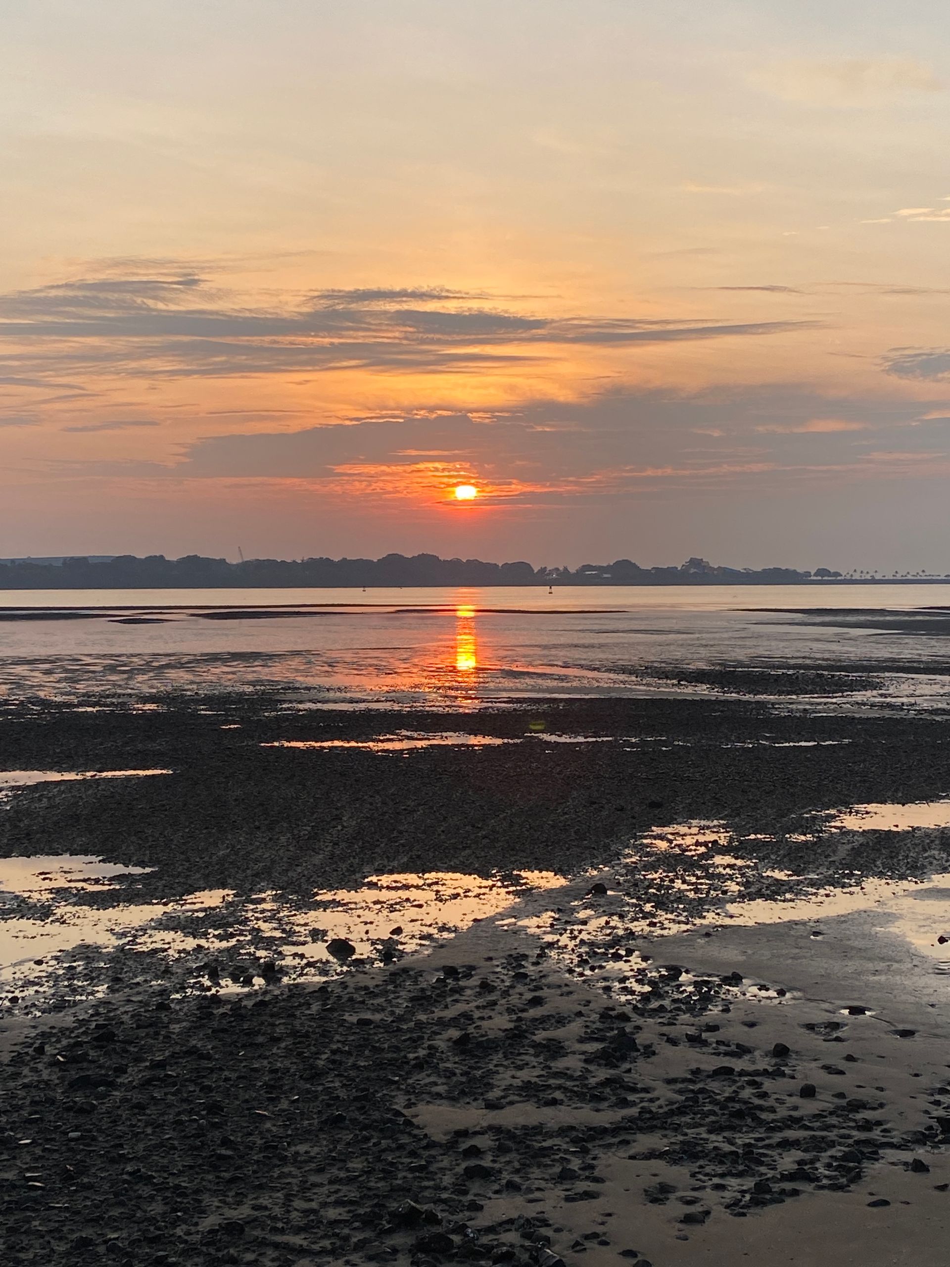 Sunset over a rocky shore, with golden light reflecting on the water.