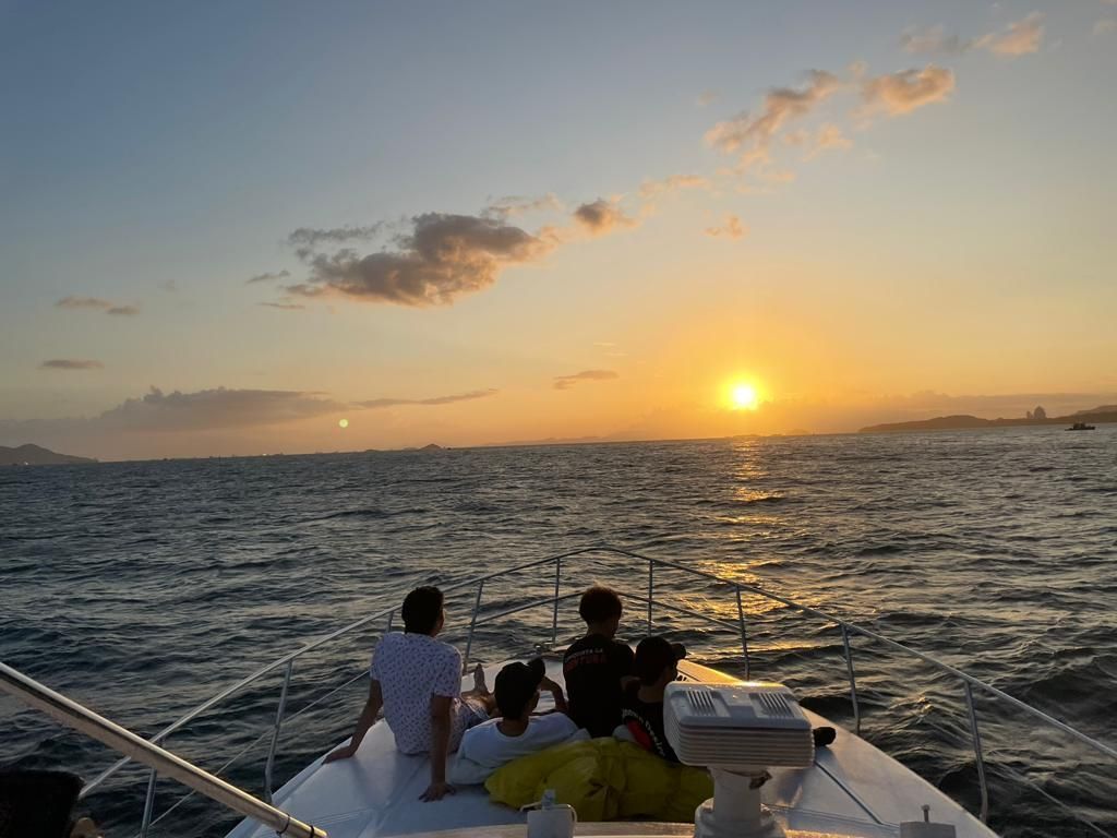 People on a boat watch the sunset over the ocean.