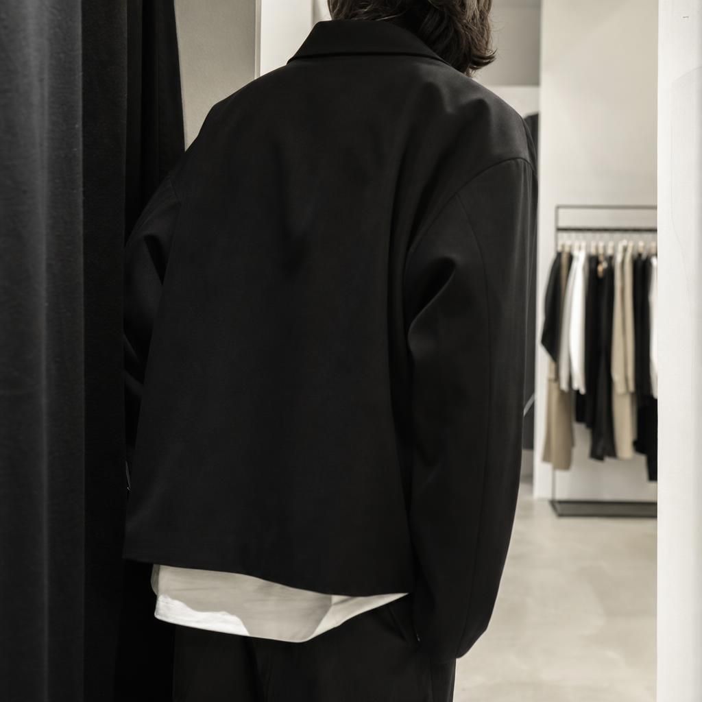 Cropped figure in black coat inside minimalist boutique