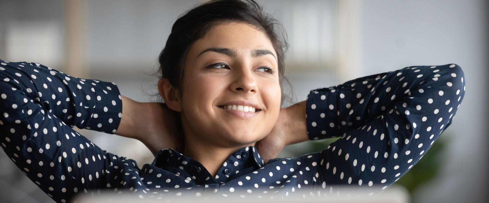 A woman is sitting with her hands behind her head and smiling Integrating Acupuncture into Your Self-Care Routine