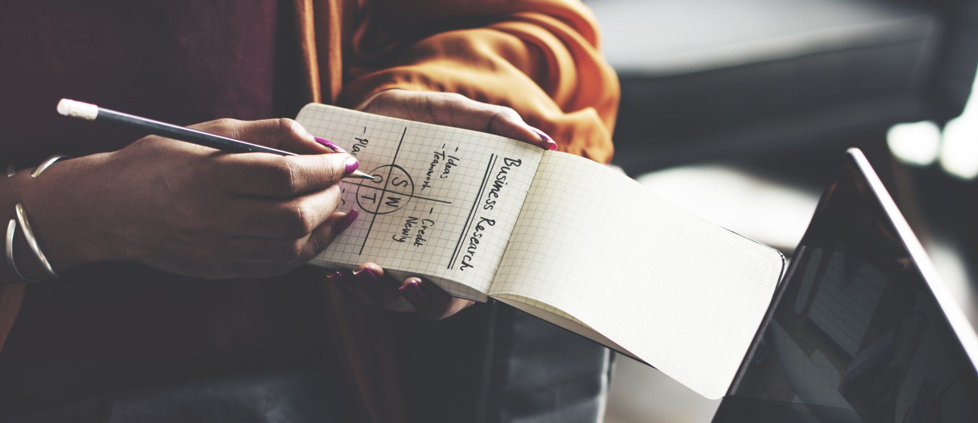 Woman holding pen and paper with SWOT acronym written on it