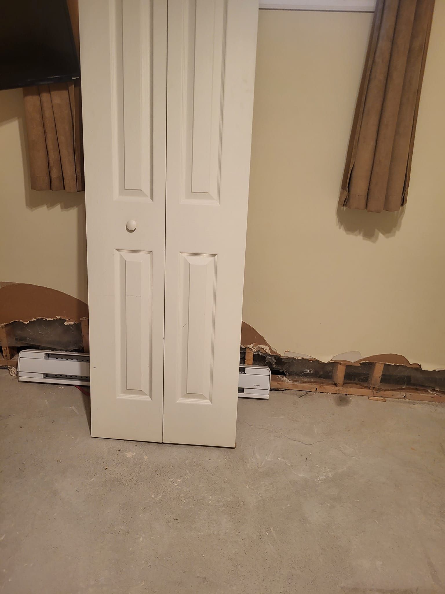Une paire de portes blanches est posée sur un sol recouvert de moquette dans une pièce.