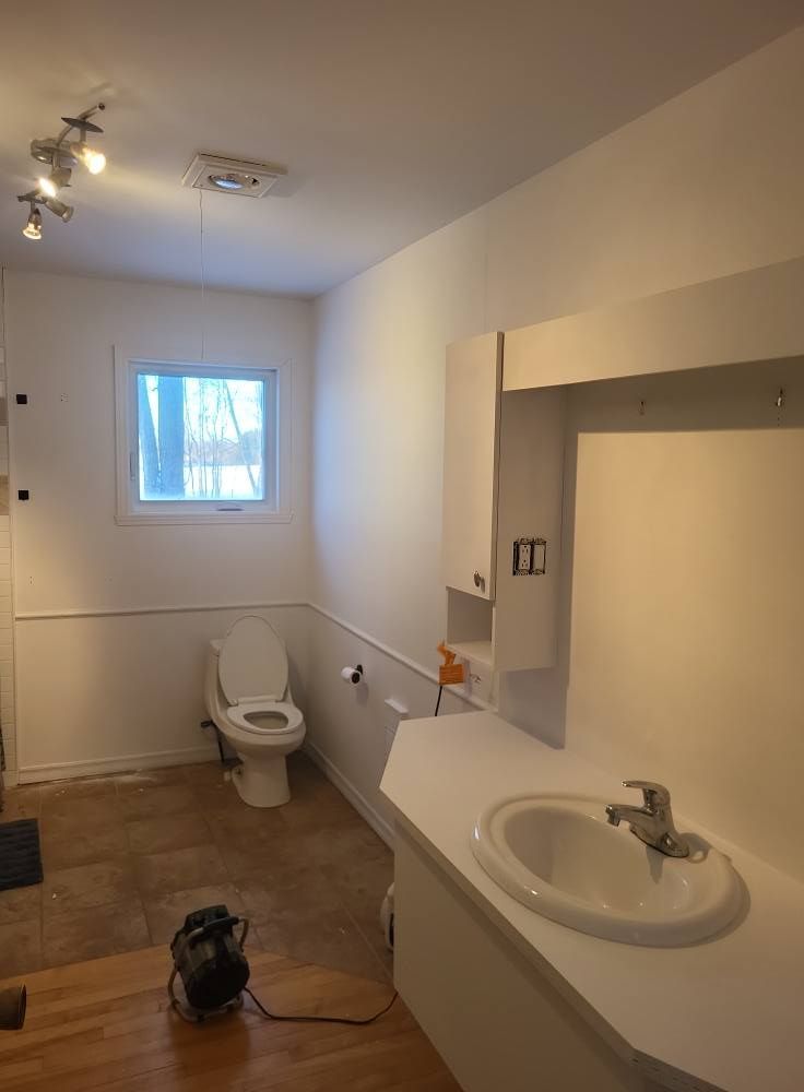 Une salle de bain avec des toilettes, un lavabo et une fenêtre