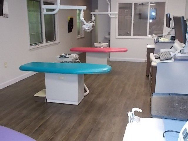 Dental office with two colorful patient chairs, equipment, and windows.