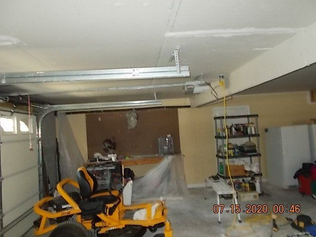 Garage interior with a lawnmower, workbench, tools, and garage door opener.