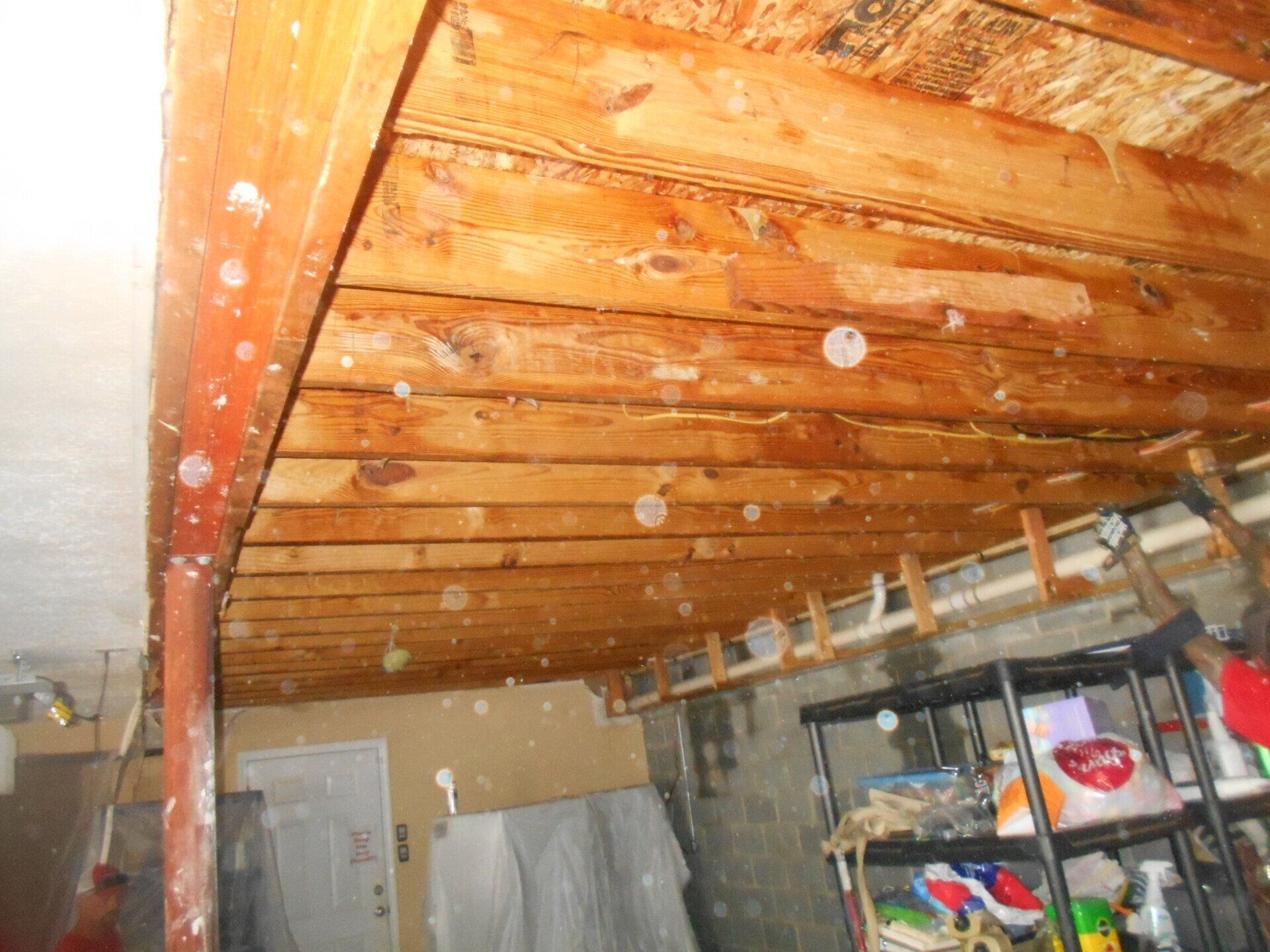 Wooden basement ceiling with visible water damage and mold.