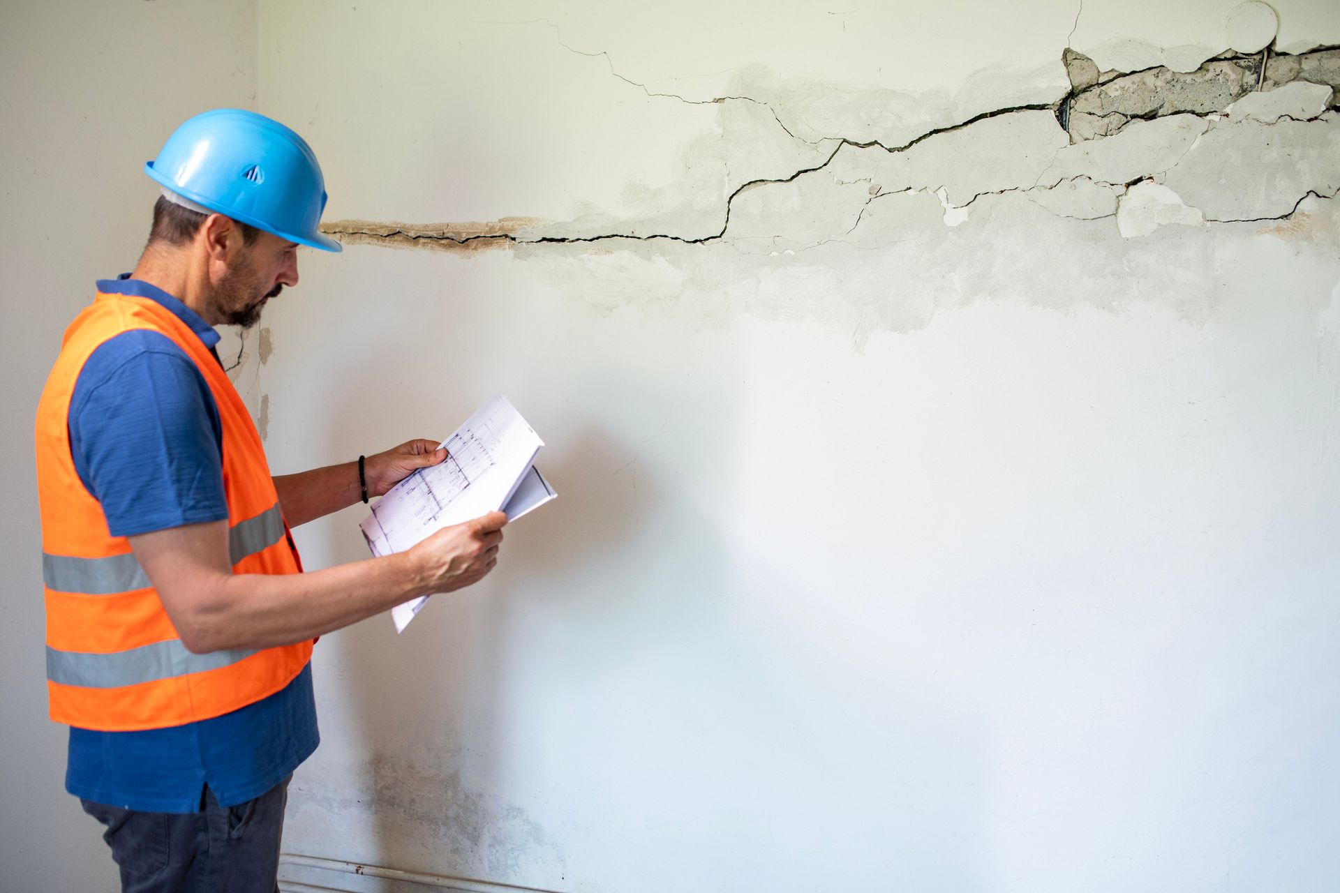 A man stands beside a cracked, damp wall, recognizing the urgent need for water damage cleanup. A man stands beside a cracked, damp wall, recognizing the urgent need for water damage cleanup.