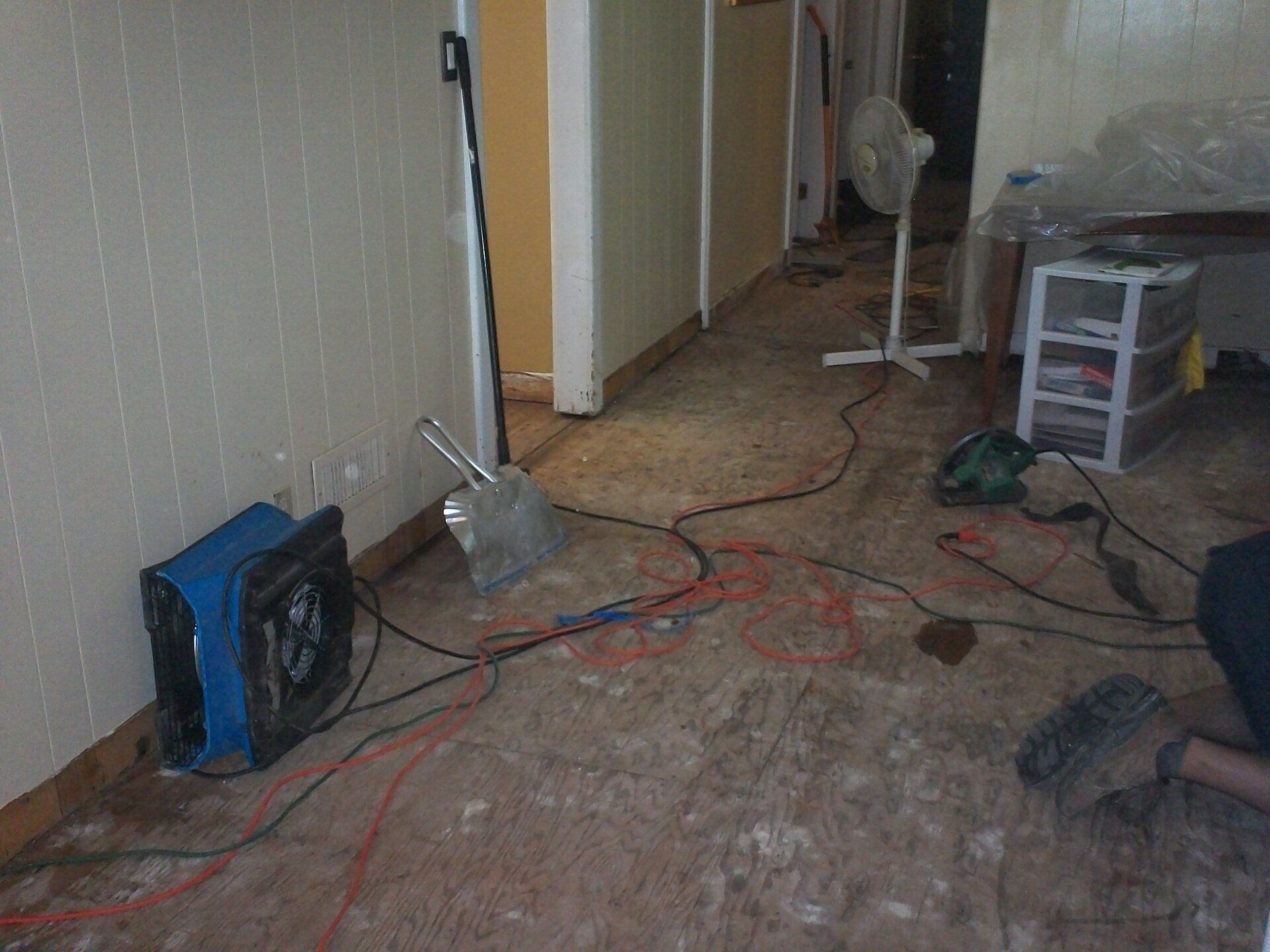 Hallway with exposed flooring, tools, and electrical cords; appears under construction.