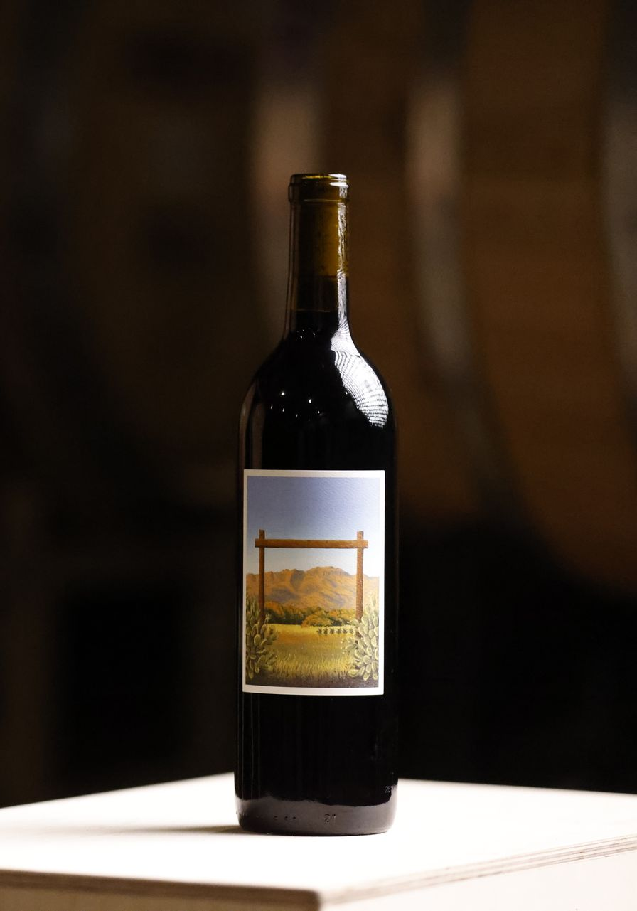 Wine bottle with a landscape label on a white table against a dark background