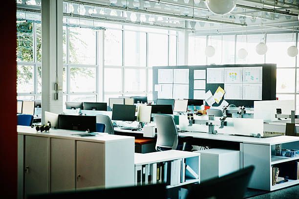 A messy office with a round table and chairs